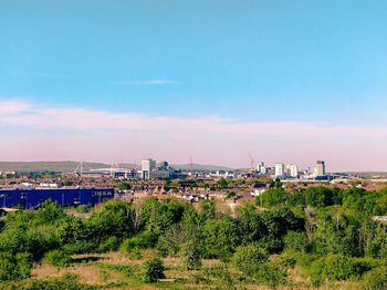 Hilltop view of city against blue summer sky with stadium and offices from hiking hill in wales