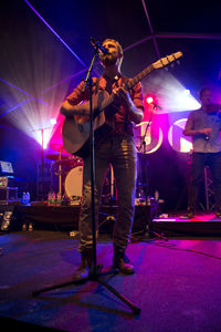 Man playing guitar at illuminated stage