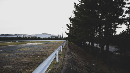 Road by trees in city against clear sky