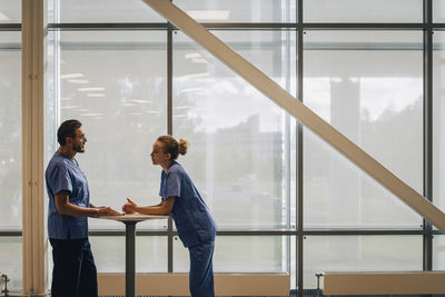 Side view of hospital staff discussing while standing by window in hospital