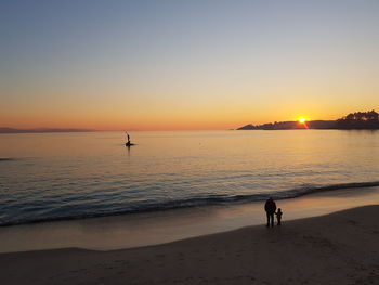 Silhouette people on beach against sky during sunset