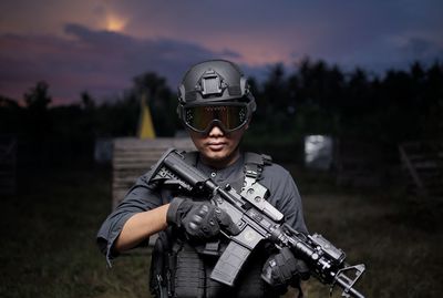 Rear view of man standing on field with weapons and equipment at night