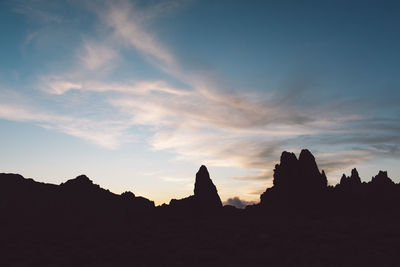 Silhouette of rocks against cloudy sky