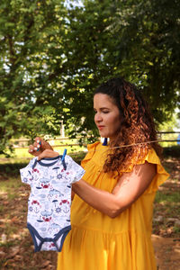 Young pregnant woman hanging laundry of her about-to-be-born baby boy