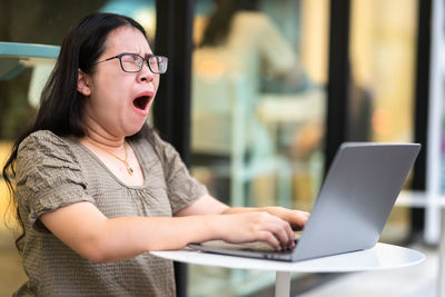 Midsection of woman using mobile phone at table