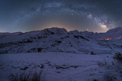 Scenic view of snowcapped mountains against sky at night