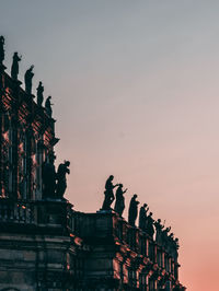 Low angle view of silhouette statues against sky during sunset