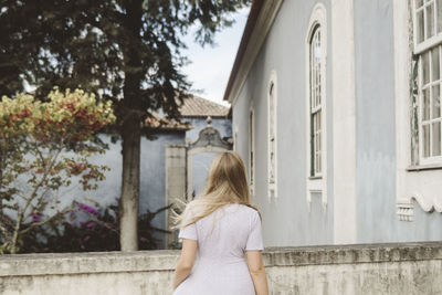 Rear view of woman standing by building