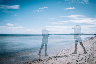 Digital composite image of women photographing with beach against sky