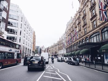 Cars on street in city against clear sky