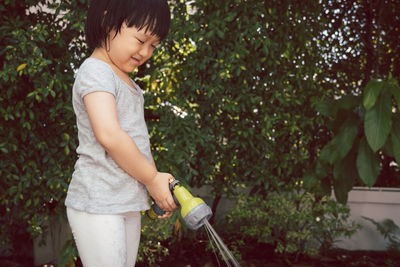 Full length of girl standing against plants in yard