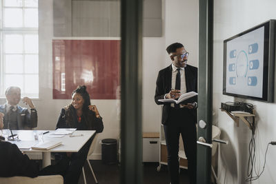 Male and female business colleagues discussing over presentation in board room at office