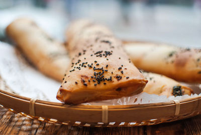 Close-up of breads in wicker plate on wooden table at bakery