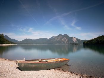 Boat on stony shore of mountain lake walchensee. warm spring morning with reflection of mountains