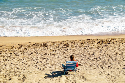 Rear view of man sitting on beach