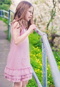Side view of girl standing by railing