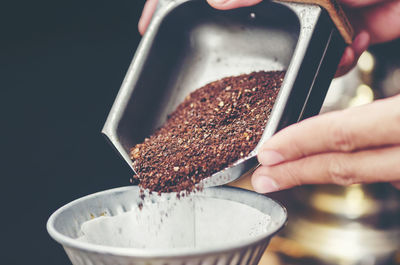 Cropped hands pouring grounded coffee in filter