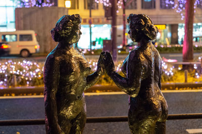 Statue against illuminated city at night