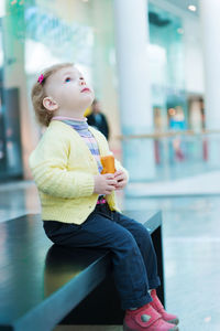 Cute girl eating food while looking away while sitting at mall