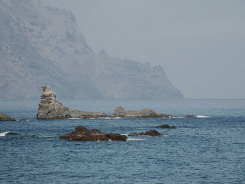Rock formation in sea against sky