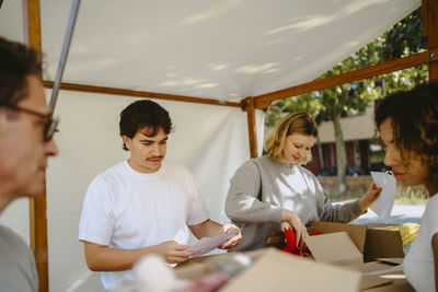Group of multiracial volunteers labeling boxes during charity program at community center