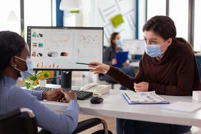 Businesswoman wearing mask having discussion with colleague