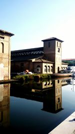 Reflection of built structure in water against clear sky