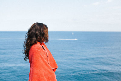 Side view of woman standing on shore at beach against sky