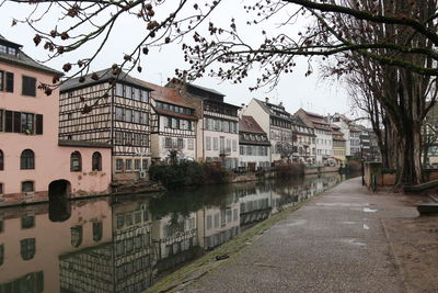 Buildings by river in city against sky