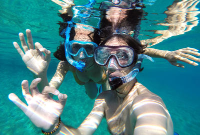 Couple showing ok sign while snorkeling in sea