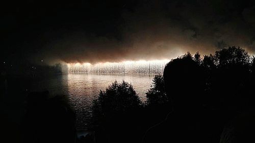 Reflection of silhouette trees in calm lake