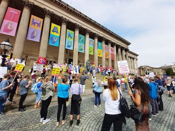 People standing on street in city against sky