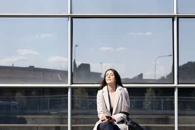 Woman looking away while sitting on window