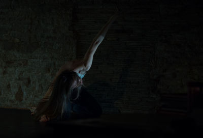 Woman dancing against wall in darkroom