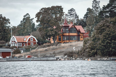 Houses by river and buildings against sky