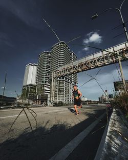 Man on street against sky in city