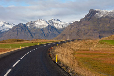 Road leading towards mountains against sky