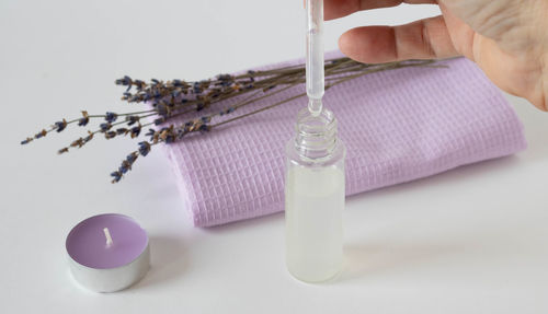 Sprigs of dried lavender and an aromatic  candle with a lilac towel, a bottle with an eyedropper