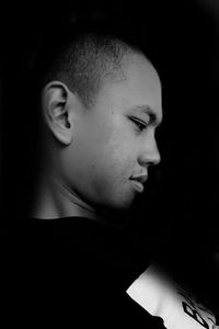 Close-up of young man looking away against black background