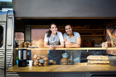 Portrait of smiling female owners in food truck parked in city