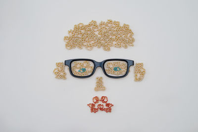 Directly above shot of human face made with eyeglasses and pasta on white background