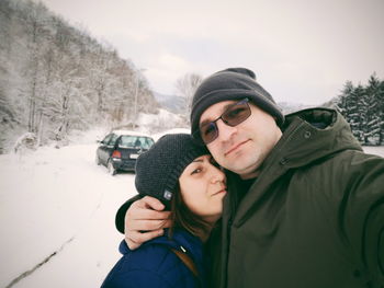 Portrait of couple embracing against sky during winter