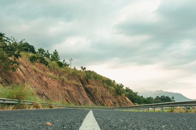 Low angle view of dividing line on the road against mountain and sky