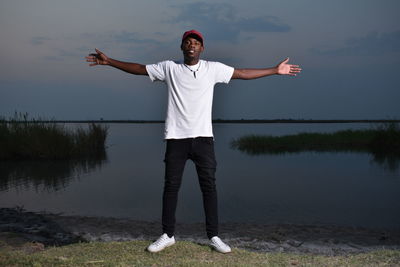 A young man from africa by the riverside having his arms outstretched