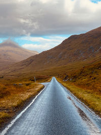 Empty road amidst mountains against sky