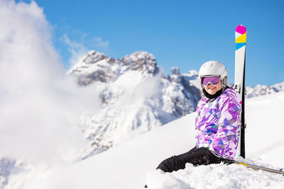Low angle view of woman standing on snow covered mountain against sky