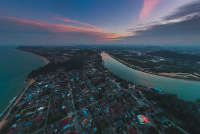 High angle view of sea by buildings against sky during sunset