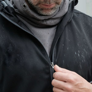 Midsection of man zipping wet jacket during rainy season