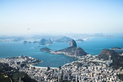 Aerial view of buildings by sea against clear sky