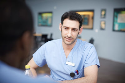 Confident male nurse talking with coworker at hospital cafeteria